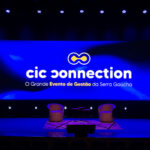 Telão com o logo do evento CIC Connection. É possível ver, também, a tagline “O Grande Evento de Gestão da Serra Gaúcha”.