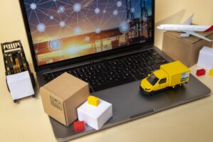 Imagem de laptop ao lado de veículos e cargas em miniatura, representando a digitalização e o uso de marketing B2B.